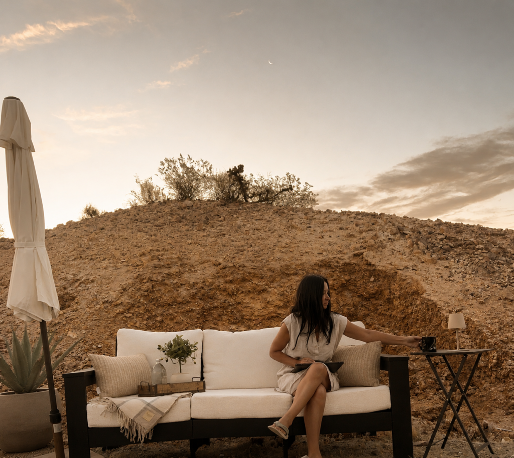 A lady grabbing a coffee while sitting on an outdoor couch enjoying the evening at Vegas Glamping 
